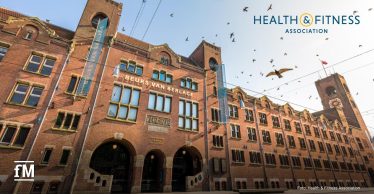 Fassade des Beurs van Berlage in Amsterdam mit Backsteinarchitektur und Schriftzug über dem Eingang. Oben rechts das Logo der Health & Fitness Association.