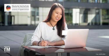 Im Vordergrund sitzt eine Person an einem Tisch vor einem Laptop und schreibt in ein Notizbuch. Links oben steht das Logo mit dem Text „Deutsche Hochschule für Prävention und Gesundheitsmanagement University of Applied Sciences“.