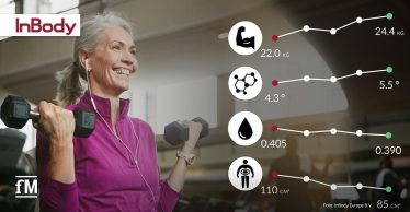 Ältere sportliche Frau mit grauen Haaren trainiert im Fitnessstudio mit Kurzhanteln, während daneben grafisch ihre verbesserten Fitnesswerte zu Muskelmasse, Phasenwinkel, EZW-Verhältnis und viszeralem Fett dargestellt werden. Diese sind für Longevity wichtig.
