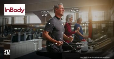 Eine Trainingssituation im Fitnessstudio, bei der Gesundheitsparameter wie Blutdruck, Muskelmasse, Handkraft und Körperfett visuell eingeblendet werden