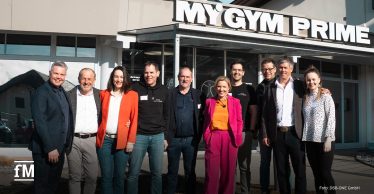 Zehn Vertreterinnen und Vertreter der Markenallianz Österreich (EGYM, seca, MATRIX, DSB-ONE, Sensopro und Wellpass) stehen lächelnd vor dem Fitnessstudio. Sie tragen legere bis elegante Kleidung. Im Hintergrund ist die gläserne Fassade des Studios zu sehen.