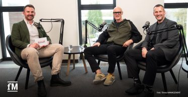 Janosch Marx, Phillip Mills und Jens Schulze sitzen zu einer Podcastaufnahme mit Mikrofonen in schwarzen Sesseln.