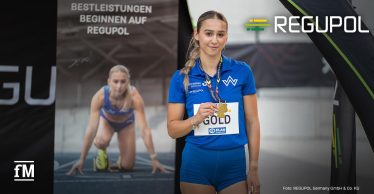 Jolina Ernst hält vor einem REGUPOL-Motiv ihre Goldmedaille in die Kamera.