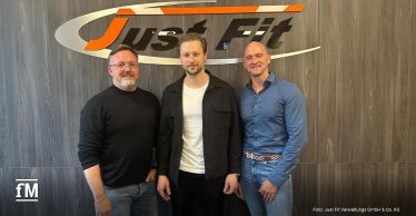 Marc Holthausen, Samuel Zabel und Oliver Neverla stehen vor dem Just Fit Logo.