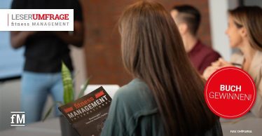 Eine Frau hält das Magazin 'fitness MANAGEMENT' in der Hand. Im Hintergrund sitzen weitere Personen an einem Tisch. Oben steht 'Leserumfrage', daneben ein roter Kreis mit 'Buch gewinnen!'.