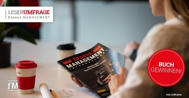 Person im rechten Bildbereich hält ein Exemplar des Magazins „fitness MANAGEMENT international“ in den Händen. Auf dem Tisch im Vordergrund stehen zwei Kaffeebecher und ein Notizblock. Links oben befindet sich das Logo „LESERUMFRAGE fitness MANAGEMENT“, rechts ein roter Kreis mit der Aufschrift „BUCH GEWINNEN!“. Unten links ist das fM-Logo sichtbar.