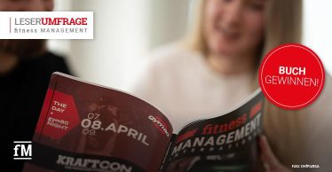 Zwei Personen blättern in einer Ausgabe des Magazins fitness MANAGEMENT international. Ein roter Kreis mit der Aufschrift 'Buch gewinnen!' hebt eine Gewinnaktion zur Leserumfrage hervor.
