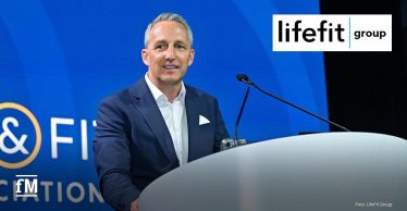 Ein Mann im Anzug (Martin Seibold) steht an einem Rednerpult vor blauem Hintergrund mit HFA-Schriftzug