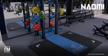 Aus erhöhter Perspektive ein dunkel gestalteter Fitnessraum mit blauschwarzem FIBEX-Rack mittig, Langhantel mit grünen und gelben Gewichtsscheiben, roten und blauen Gewichtsscheiben an den seitlichen Ablagen, schwarzer und blauer Bodenfläche mit FIBEX-Schriftzug vorn rechts, Kurzhantelablagen rechts im Hintergrund, Trainingsgeräten links im Hintergrund, NAOMI FITNESS DESIGN-Schriftzug oben rechts, fM-Logo unten links und Foto: NAOMI FITNESS DESIGN unten rechts.