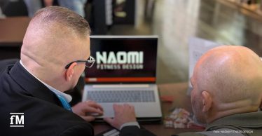 Zwei Personen betrachten an einem Laptop eine Präsentation von NAOMI FITNESS DESIGN.