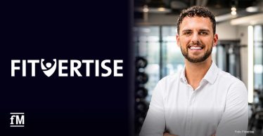 Rechts im Vordergrund steht ein Mann mit weißem Hemd und verschränkten Armen vor unscharfem Fitnessstudioumfeld. Links befindet sich auf dunklem Hintergrund das Logo „FITVERTISE“.