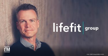 Porträt von Dr. Nick Weinberger vor einer Wand, rechts im Bild das Logo der LifeFit Group.