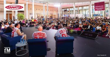 Bodybuilder sitzen auf einer Bühne vor einem großen Publikum in der RiminiWellness-Arena.
