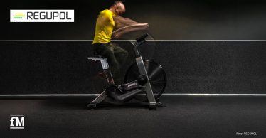 Person trainiert auf einem Airbike vor einer dunklen Wand.