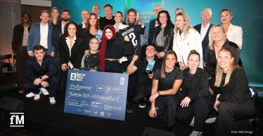 Großes Gruppenfoto von rund 25 Personen mit Award-Trophäen und großem Scheck auf einer Bühne vor European-Fitness-Award-Logowand.