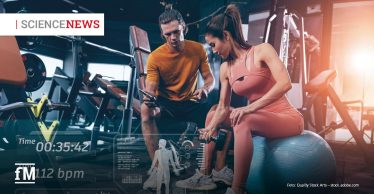 Frau trainiert im Fitnessstudio mit Kurzhanteln, ein Trainer schaut auf ein Tablet; eingeblendete Fitnessdaten überlagern das Bild. Links oben steht Science News.