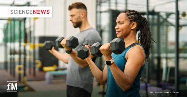 Im Vordergrund führt eine Frau in blauem Sportoberteil mit zwei Kurzhanteln eine Bizepscurl-Bewegung aus. Links dahinter trainiert ein Mann mit Kurzhanteln. Im Hintergrund befinden sich Trainingsgeräte in einem Fitnessstudio. Oben links steht der Schriftzug „SCIENCE NEWS“, unten links das Logo „fM“.
