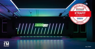Moderner Kursraum mit beleuchteter Bühne, XTRAFIT-Schriftzug und auffälligem Lichtdesign.