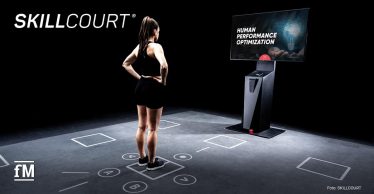 Eine Athletin steht auf markiertem Trainingsfeld vor einem SKILLCOURT-Bildschirm.