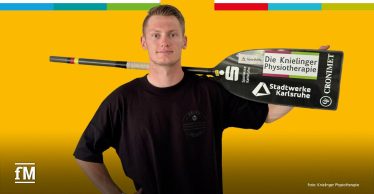 Mann steht frontal vor gelbem Hintergrund und hält ein Kanu-Paddel auf der Schulter; auf dem Paddel stehen „Die Knielinger Physiotherapie“, „Stadtwerke Karlsruhe“ und „CROMAET“; links unten das fM-Logo.