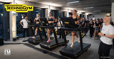 Drei Läuferinnen laufen auf Technogym-Laufbändern vor Publikum in einem Veranstaltungsraum