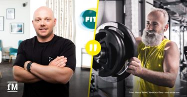 Porträt eines Mannes mit Brille und verschränkten Armen vor dunklem Hintergrund; trägt ein helles Sweatshirt mit UFC GYM Schriftzug