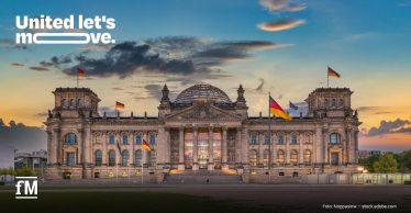 Reichstagsgebäude in Berlin mit Deutschlandflaggen und „United let's move.“-Logo