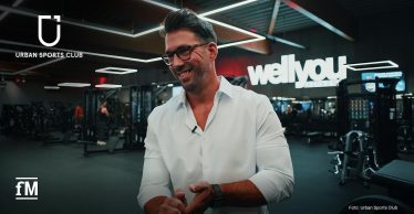 Trainingsfläche eines Fitnessstudios, ein Mann im weißen Hemd steht vor Geräten und Beleuchtungselementen