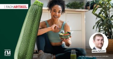 Sportliche Person bereitet eine vegane Mahlzeit mit Gemüse, Hülsenfrüchten und Getreide zu.