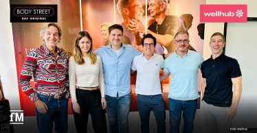 Gruppenfoto von sechs Personen aus dem Fitness- und Gesundheitsbereich, die nebeneinander in einem Studio stehen und in die Kamera lächeln